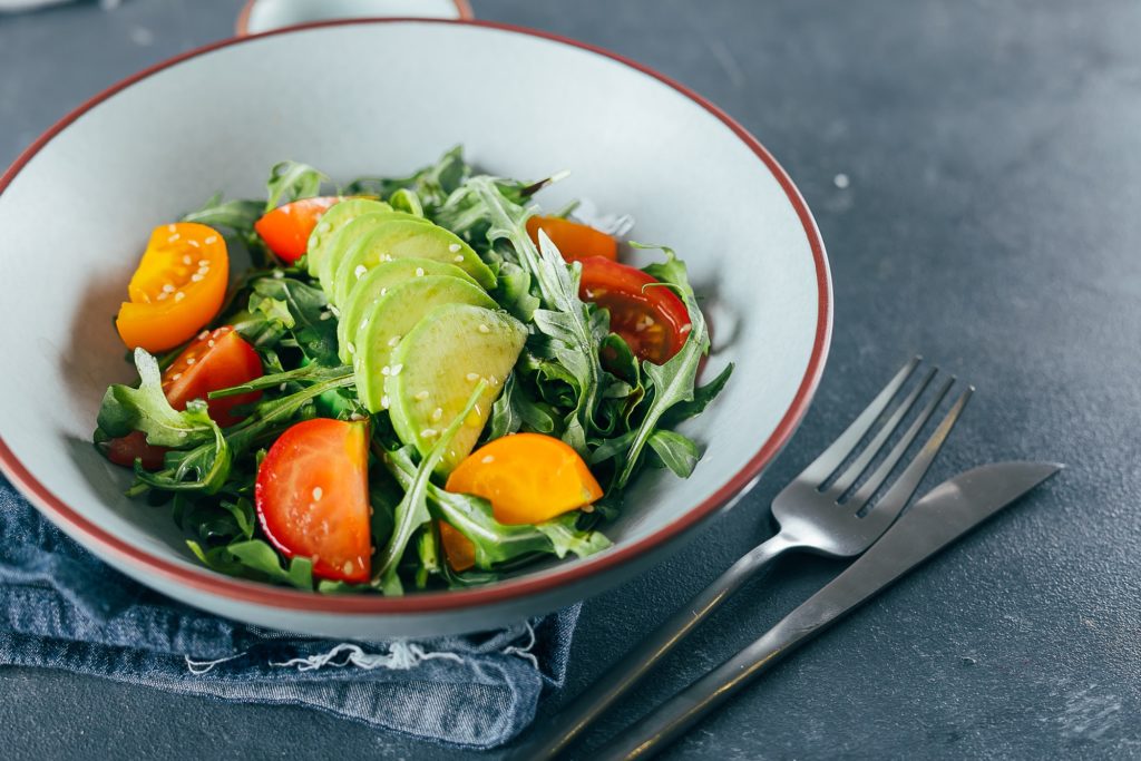 Healthy vegan salad with tomato, arugula, avocado and sesame. Vegan diet menu.